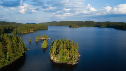 Small islands with pine-trees in the middle of Isojarvi lake.  Beautiful landscape scenery with clear blue water in National park. Finland, Europe.