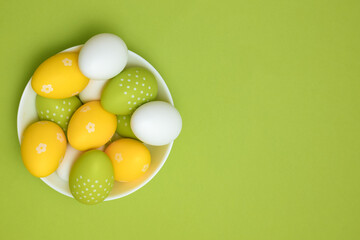 Colorful Easter eggs in a plate on a green background. Green, yellow and white Easter eggs. Spring mood.	

