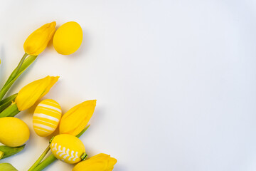 Easter background with yellow  eggs and yellow tulips. Top view with copy space. Easter postcard. Spring and Easter holiday flat lay. Minimal easter concept. Paschal greeting card.