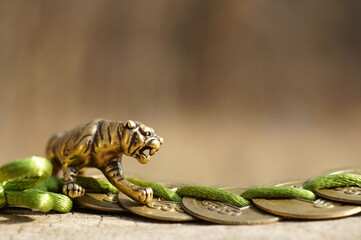 Metal tiger figurine close-up. Next to it is a bunch of Chinese coins.