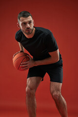 Focused seriously sportsman in black sportswear training isolated on red background