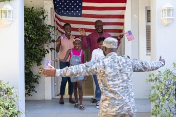 African american soldier father with wife, children and father greeting him outside their house