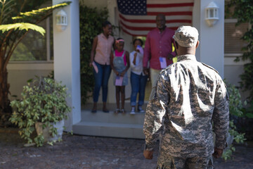 African american soldier father in front of wife, children and father greeting him outside house