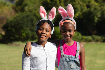Portrait of happy african american brother and sister embracing wearing bunny ears outdoors