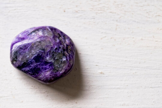 Pierre roul&eacute;e polie charoite sur un fond blanc - Min&eacute;ral naturel