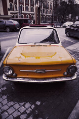 Obraz na płótnie Canvas retro car auto yellow on the street of the city small funny