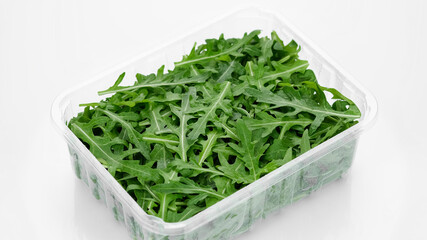 fresh arugula in container for delivery or sale on white background