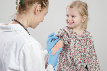 Doctor looking at red and itchy eczema on little girl's arm. Toddler girl suffering from atopic...