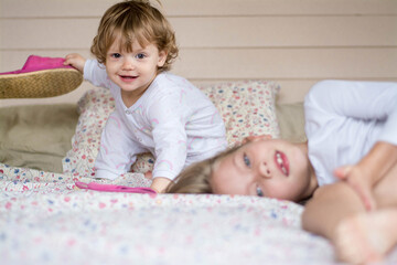 Two girls are playing on the bed.