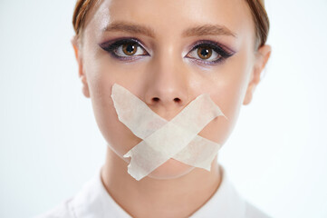 Headshot of woman with taped mouth