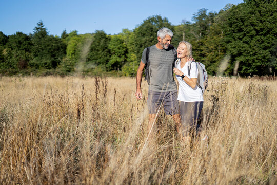 Smiling mature couple hiking in forest - Powered by Adobe