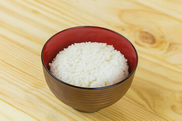 Cooked jasmine rice in white bowl on wooden table and dark background with copy space,high calories food,Top view..