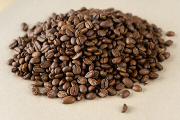 a handful of roasted coffee beans on a beige background
