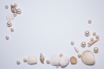 Sea shells and pearls on the white background, with free space for text. Top view, elegant flat...