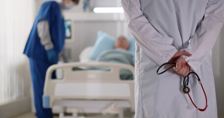 Back view of doctor holding stethoscope standing in hospital ward