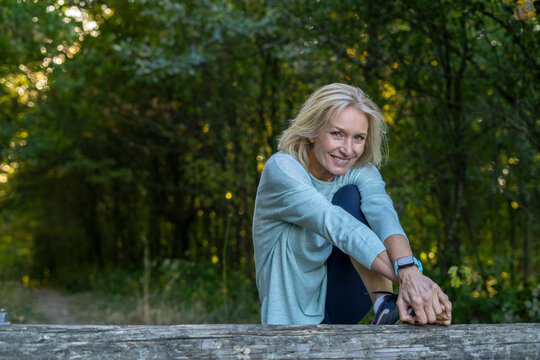 Portrait of smiling mature woman stretching her leg in forest
