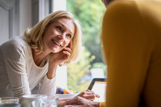 Smiling Mature Woman Looking At Her Husband While Using Digital Tablet