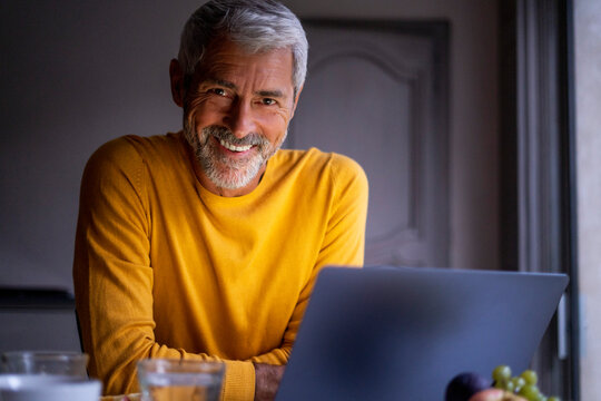 Portrait of smiling mature man using laptop at home