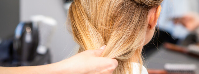 Naklejka premium Close up of hands of female hairdresser styling hair of a blonde woman in a hair salon