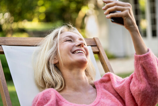 Close-up of smiling mature woman having video call on smartphone in backyard