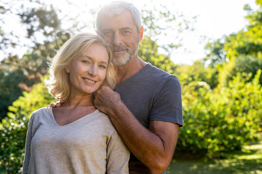 Portrait of smiling mature couple standing in backyard