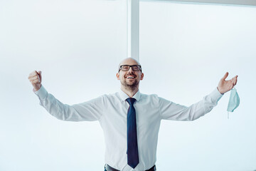 happy businessman with a protective mask standing near the office window.