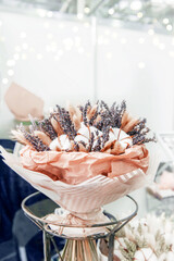 stylish bouquet of dried flowers in pastel colors made of cotton, fluffy ears and kraspedia on the counter of a flower shop. reasonable consumption of natural materials, selection of bouquets