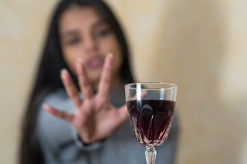 Giving up alcohol. A young woman at the table refuses with her hand a glass of red wine. Selective focus