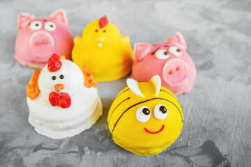 Cake in the form of animals. Homemade souffle in glaze is decorated in the form of animal faces. Pigs, chickens and bees in the form of children's cakes