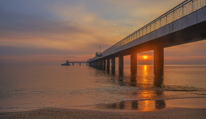 Dramatic sunrise on the beach in Burgas, Bulgaria. Sunrise on the Burgas Bridge. Bridge in Burgas - symbol of the city. 