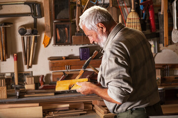 Experienced carpenter working in his workshop.Working with hand wood planer.