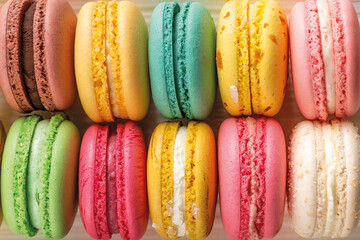 Closeup of delicious multicolored macaroons as a background. Mockup of greeting card with sweet multicolored macaron cakes. Delicious french almond meringue cookies. Copy space.