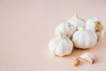 Obraz na płótnie Canvas Bulbs and cloves of garlic on a pink background, close-up. Organic garlic. Protect immune system. Copy space.