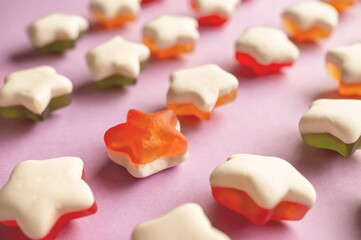 Background of jelly candies in the shape of a star. Stars of fruit marmalade on a pink solid background.