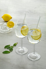 Glasses with water and lemon slice and a citrus press at the background