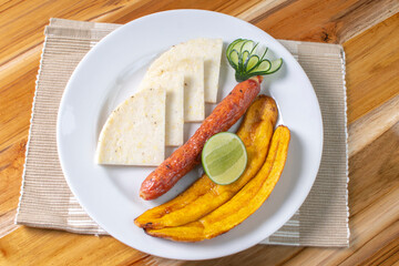 Arepa with chorizo, fried banana, lemon, traditional Colombian food, on wooden background