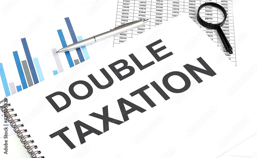 Fototapete in the notebook, the text double taxation , next to magnifier and a pen, the background is graphics.