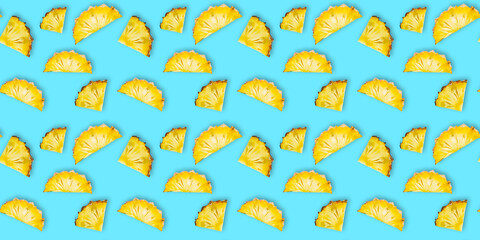 Seamless pattern of fresh ripe pineapple slices isolated on cyan background. Top view. Exotic tropical fruit summer concept