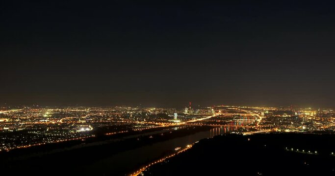 Nighttime timelapse shot of the city of Vienna overlooking the Danube river.