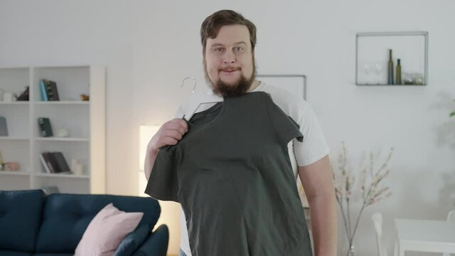 Sad overweight man trying on small size, dreaming to be slim, insecurities