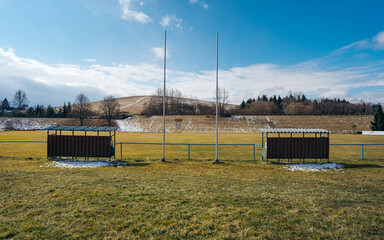 Old Seats for substitutes or reserves in village pitch. No people. Football field in the village. Soccer playground turf field. Coronavirus Covid 19 pandemic