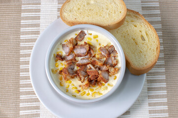 Corn flakes with gratin cheese, fried bacon accompanied by bread on wooden background