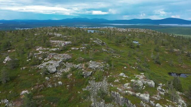 Aerial view of a hikers on sitting in rocky Lapland taiga and tundra - descending, drone shot