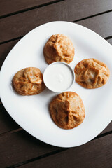 Juicy manti on a white plate. Served with sauce. Asian cuisine.