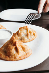 Juicy manti on a white plate. Served with sauce. Asian cuisine.