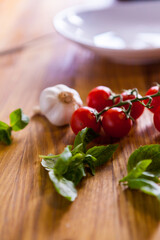 Cherry Tomatoes Mint Garlic and Eggplant Prepared to bee cooked. White plate. Vegetables on the wooden table. Fresh Cheery Tomato. Raw vegetables. Beautifull Light Photography. Macro. Close Up.