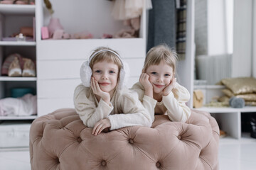 Girls sisters lie in a modern dressing room and look at the camera