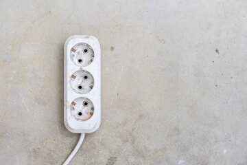 Dirty extension socket during the repair of the room on the concrete. Top view. Copy space.