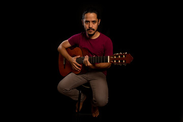 Man holding a guitar with black background