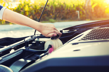 Check auto car's coolant level. That service, repair or maintenance by women hand to open cap of...